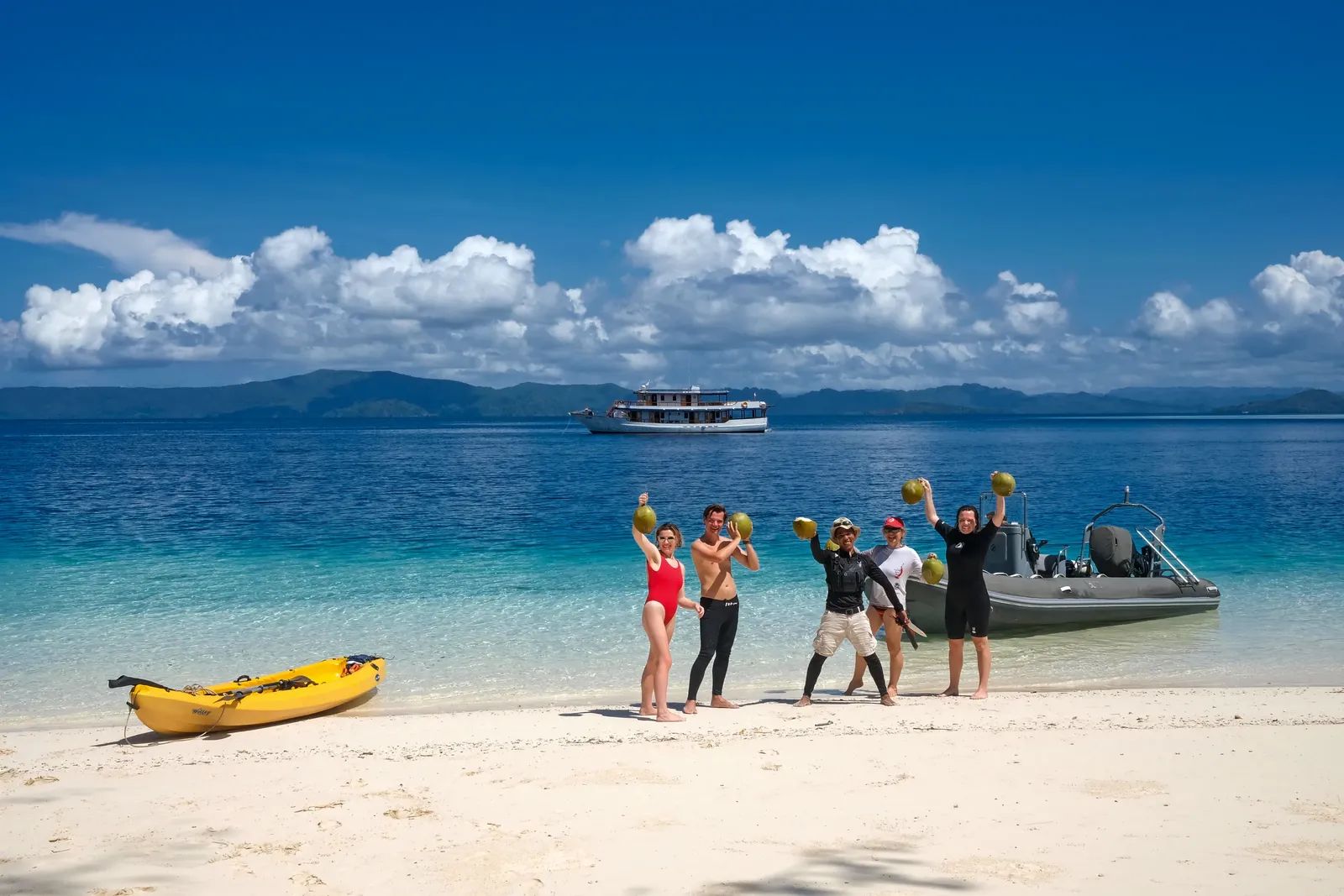Nomad Archipelago liveaboard – guests with coconuts on a beach landing – Indonesia