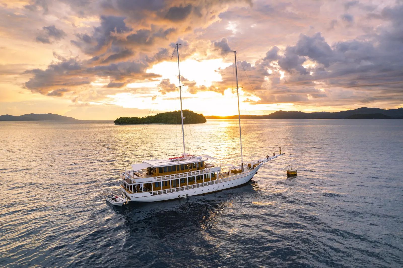 Fenides liveaboard – vessel at anchor at sunset with guests on the swim platform – Indonesia