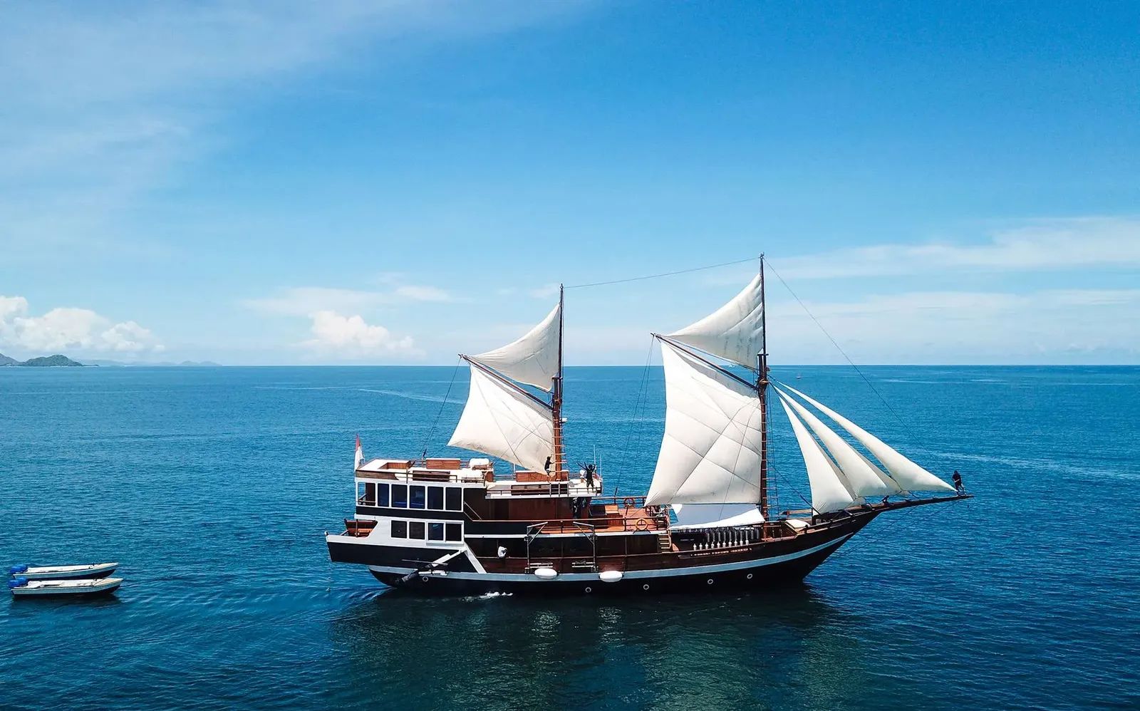 Jelajahi Laut liveaboard – traditional phinisi under sail with tenders alongside – Komodo, Indonesia
