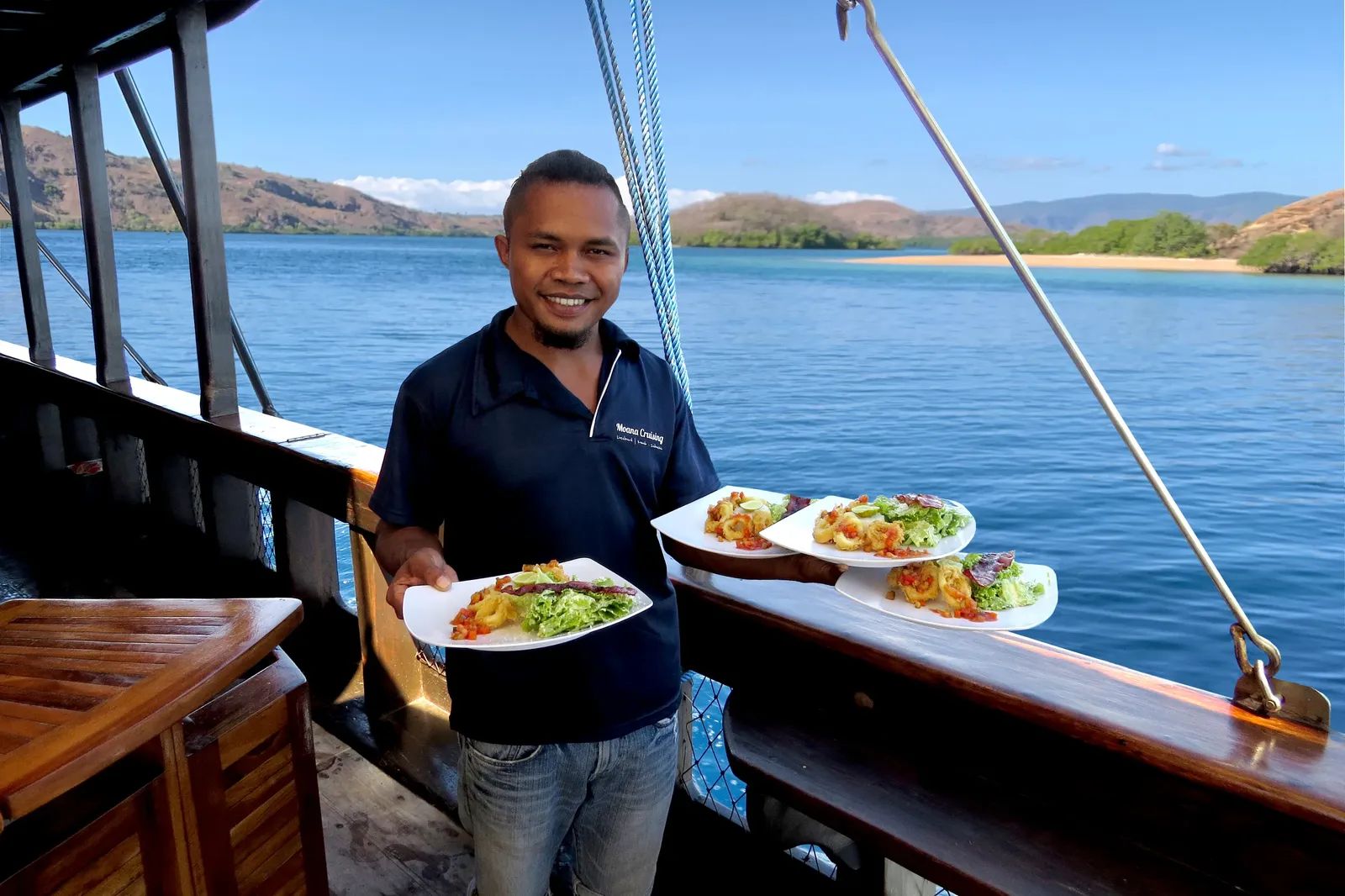 Moana Cruising liveaboard – crew member serving calamari salad plates – Komodo, Indonesia