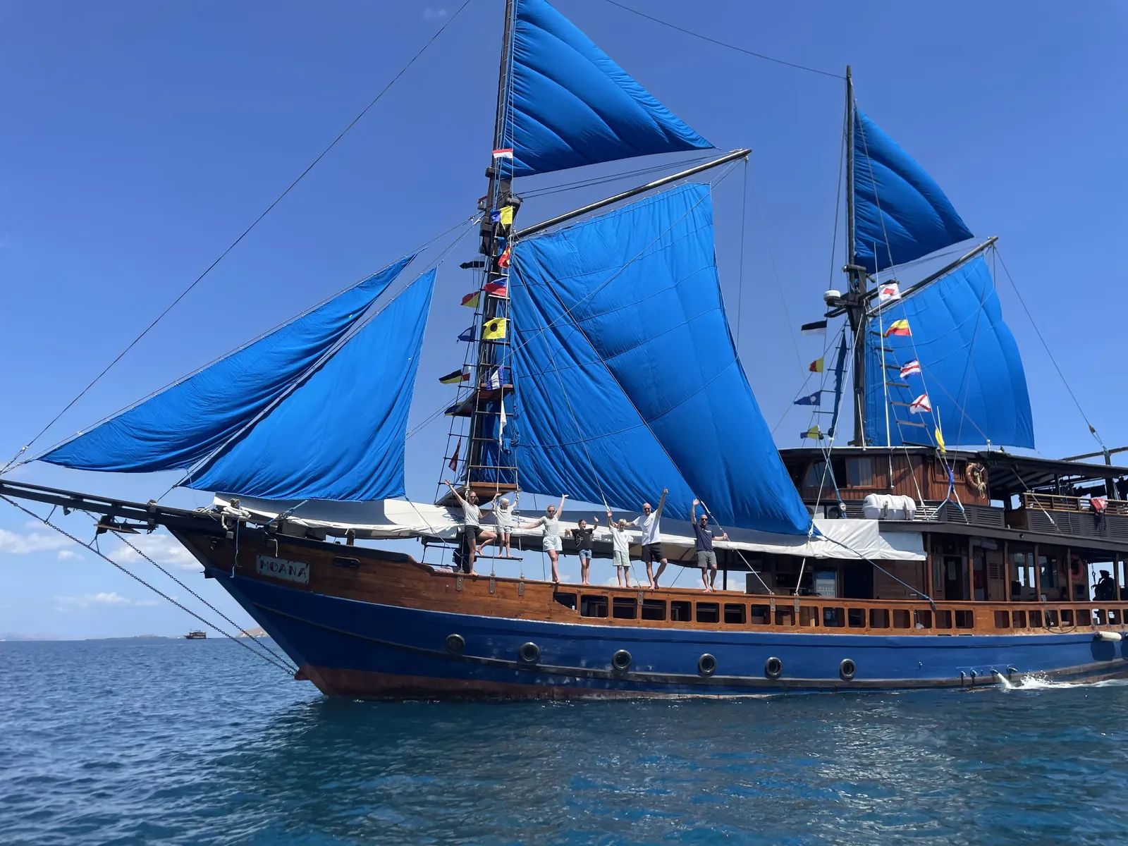 Moana Cruising liveaboard – full sails with guests on the bowsprit – Komodo, Indonesia